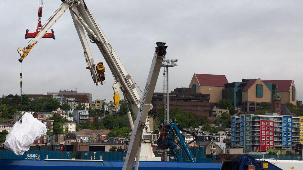 Debris from the Titan submersible lifted by crane